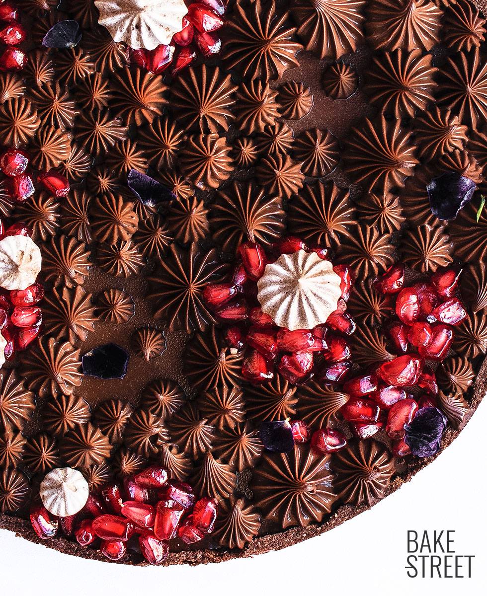 Tarta de chocolate con leche y granada, elaborada con una pâte sucrée de cacao y rellena con una ganache de chocolate con leche y canela.