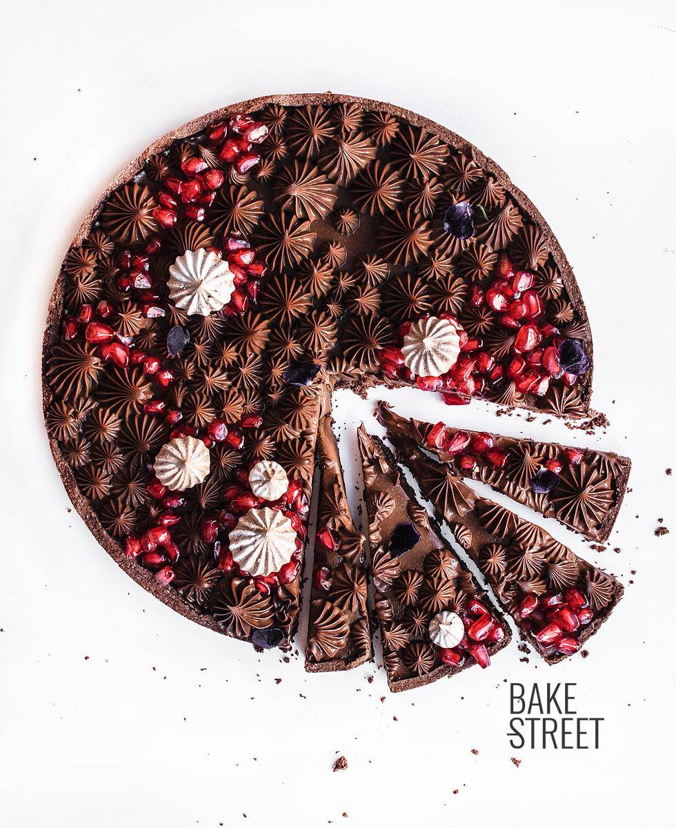 Tarta de chocolate con leche y granada, elaborada con una pâte sucrée de cacao y rellena con una ganache de chocolate con leche y canela.